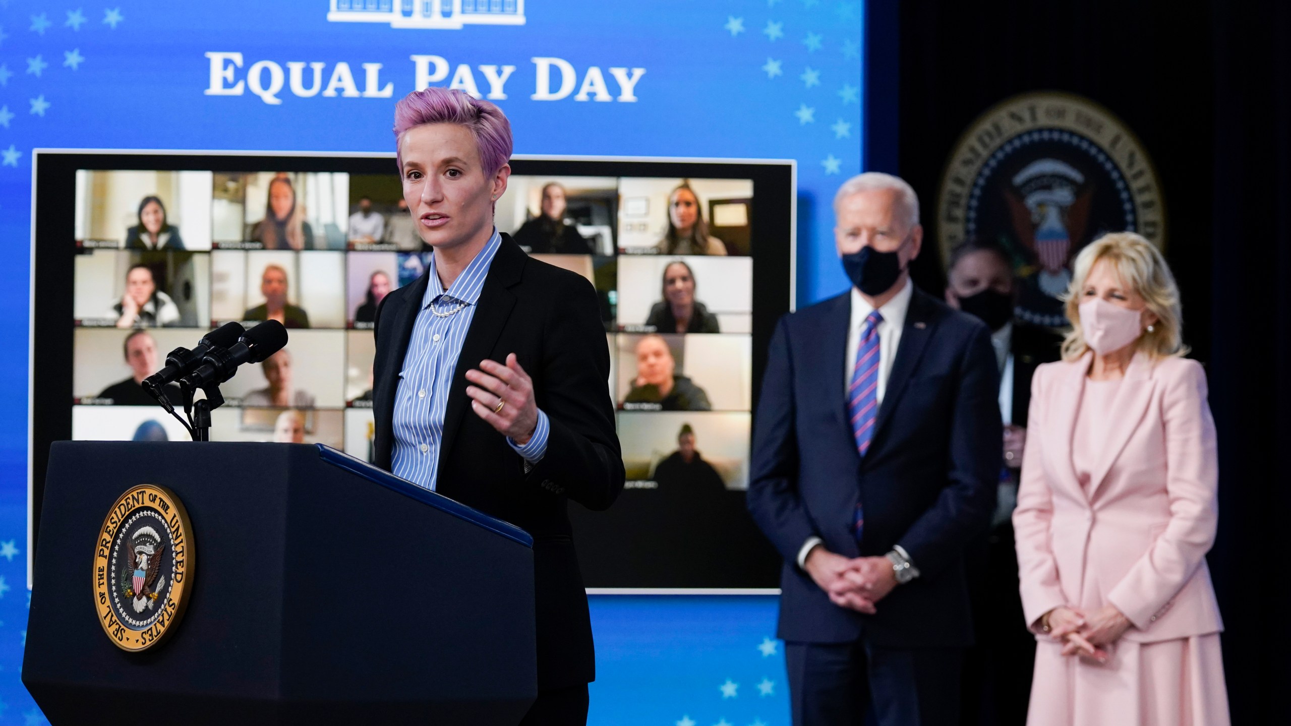 U.S. Soccer Women's National Team member Megan Rapinoe speaks as President Joe Biden and first lady Jill Biden look on during an event to mark Equal Pay Day in the Eisenhower Executive Office Building on the White House Campus on March 24, 2021. (Evan Vucci / Associated Press)