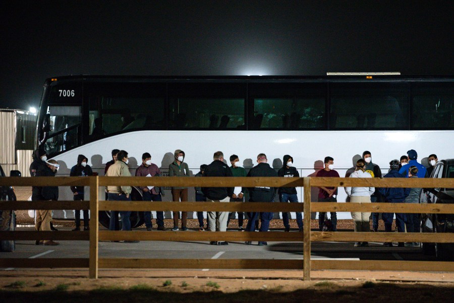 In this Sunday, March 14, 2021, file photo, migrant children and teenagers are processed after entering the site of a temporary holding facility south of Midland, Texas. The Biden administration is not requiring FBI fingerprint background checks of caregivers at its rapidly expanding network of emergency sites to hold thousands of immigrant teenagers. That alarms child welfare experts who say the waiver compromises safety. (Eli Hartman/Odessa American via AP, File)