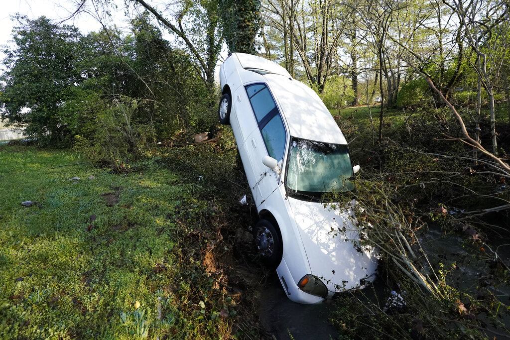 A car that was carried by floodwaters leans against a tree in a creek Sunday, March 28, 2021, in Nashville, Tenn. (AP Photo/Mark Humphrey)