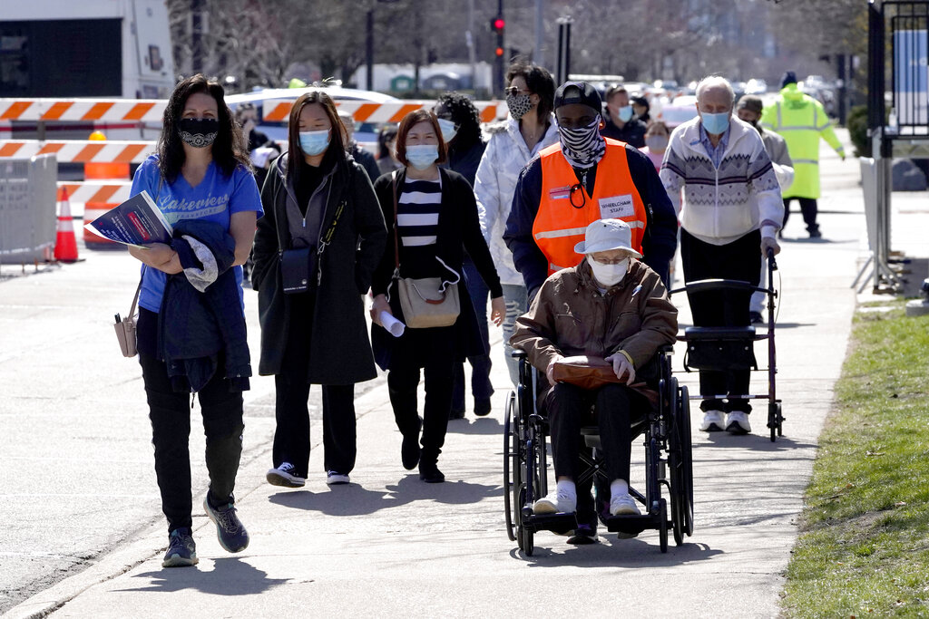 Chicago area residents pass between a drive-thru and walk-in mass vaccination site Monday, March 29, 2021, across the street from the United Center, home to the Chicago Bulls and Blackhawks in Chicago. (AP Photo/Charles Rex Arbogast)