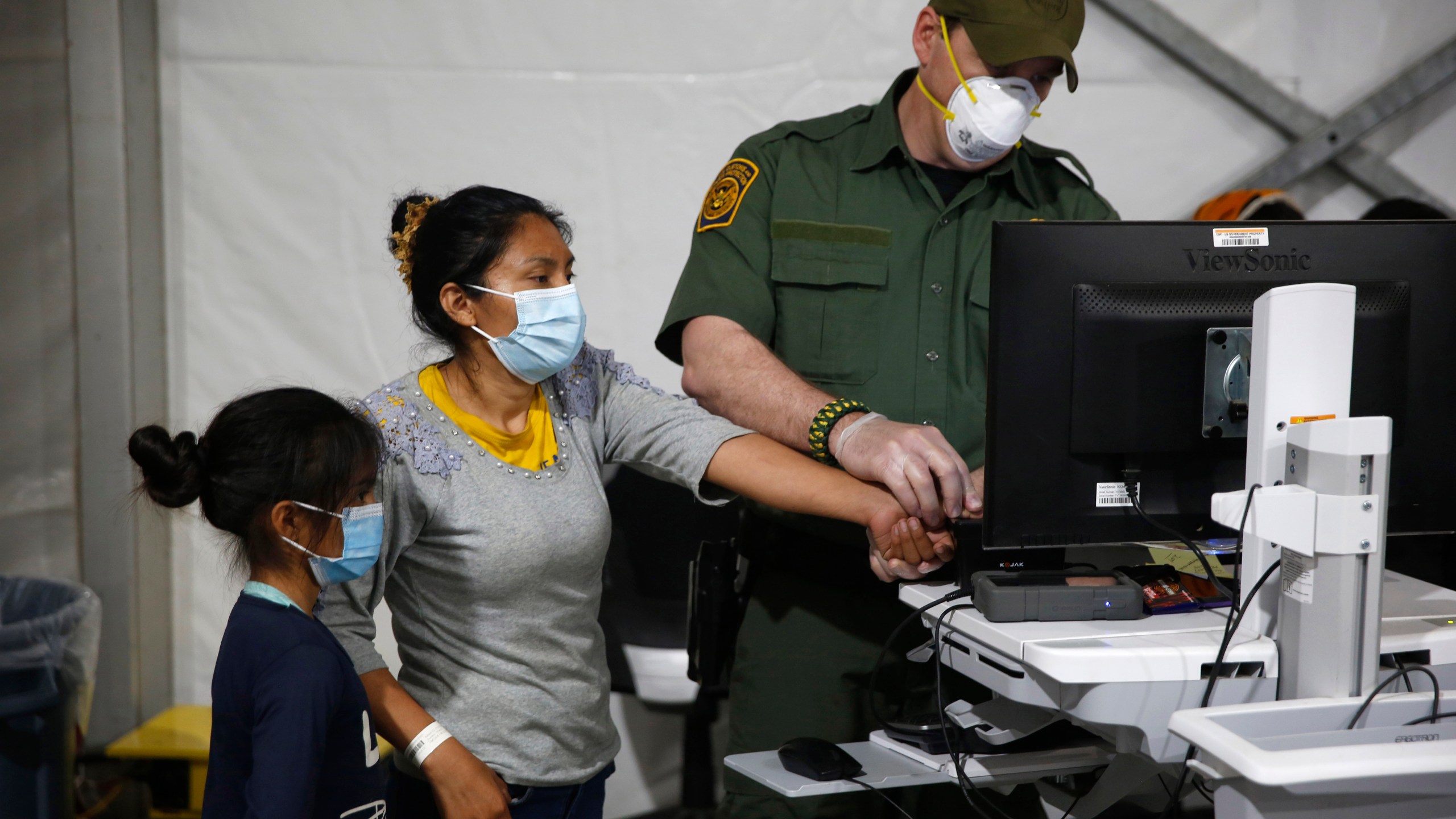 A migrant and her daughter have their biometric data entered at the intake area of the Donna Department of Homeland Security holding facility, the main detention center for unaccompanied children in the Rio Grande Valley, in Donna, Texas, on March 30, 2021. (AP Photo/Dario Lopez-Mills, Pool)