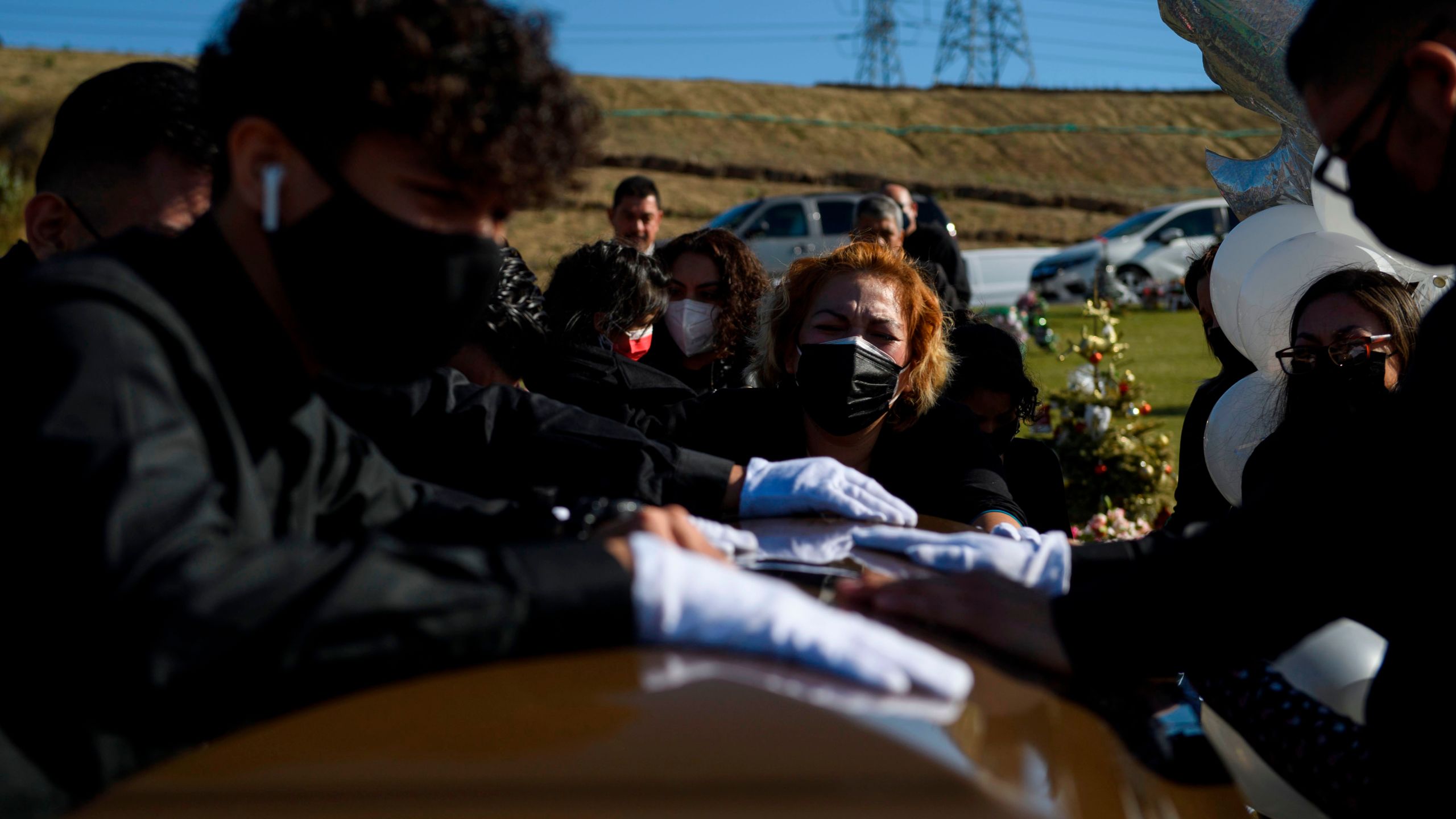 Maricela Arreguin Mejia and family members mourn over the casket of her father during a burial service for Gilberto Arreguin Camacho, 58, who died due to COVID-19, at a cemetery on New Year's Eve, Dec. 31, 2020, in Whittier, California. (PATRICK T. FALLON/AFP via Getty Images)