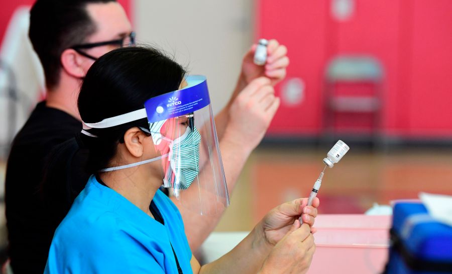 Registered nurses help transfer the Moderna COVID-19 vaccine from a bottle into a syringe ready for vaccination at the Corona High School gymnasium in the Riverside County city of Corona, California on January 15, 2021, a day after California began offering the coronavirus vaccine to residents 65 and older. (FREDERIC J. BROWN/AFP via Getty Images)