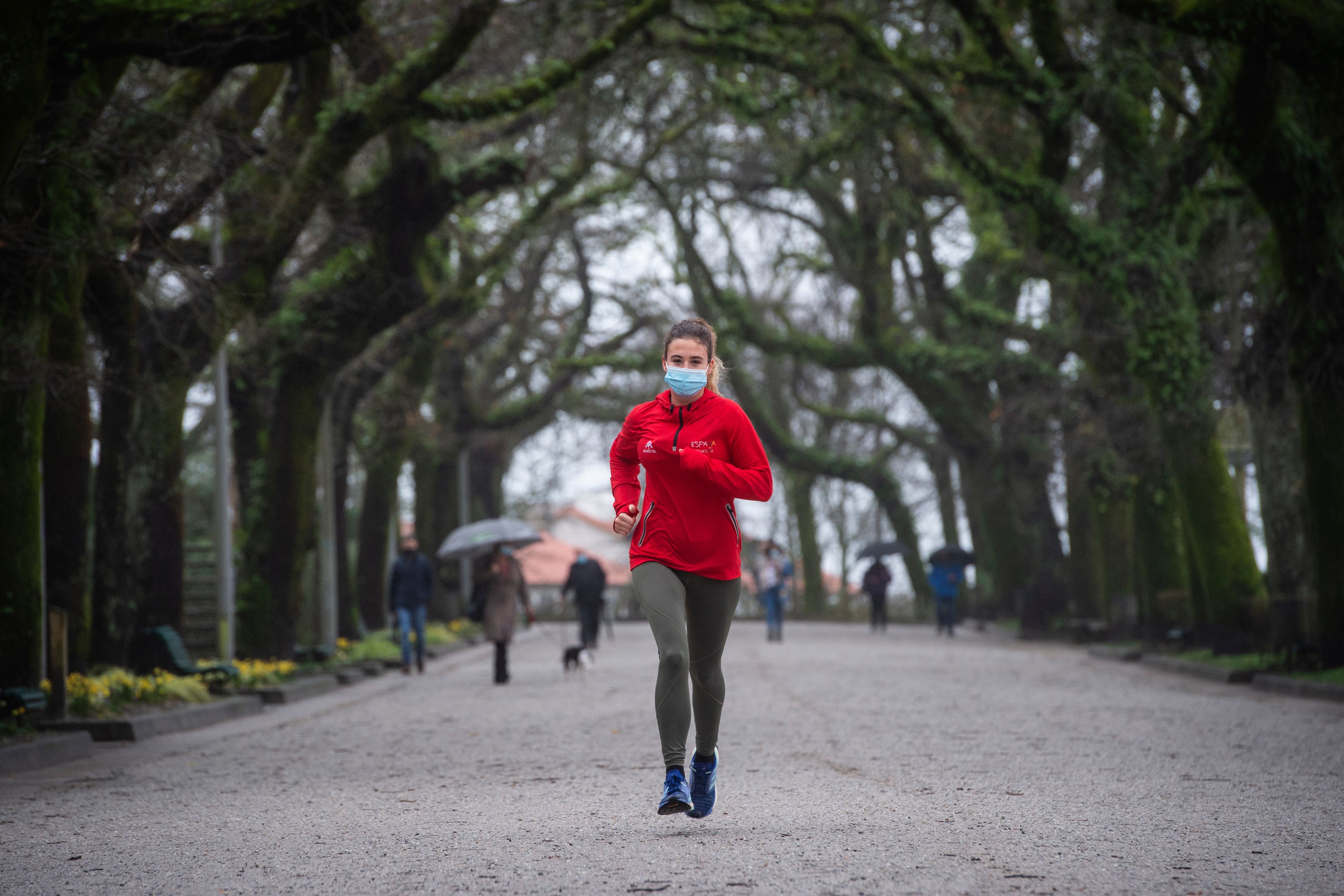 A woman wearing a face mask jogs through a park following new coronavirus restrictions in Santiago de Compostela in northwestern Spain on January 27, 2021. (MIGUEL RIOPA/AFP via Getty Images)