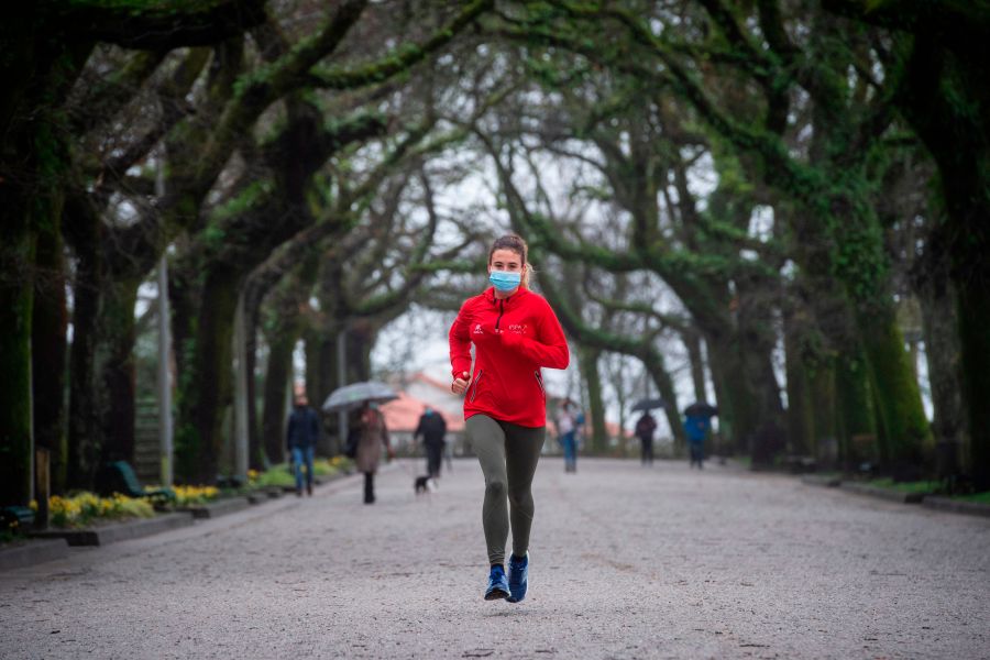 A woman wearing a face mask jogs through a park following new coronavirus restrictions in Santiago de Compostela in northwestern Spain on January 27, 2021. (MIGUEL RIOPA/AFP via Getty Images)