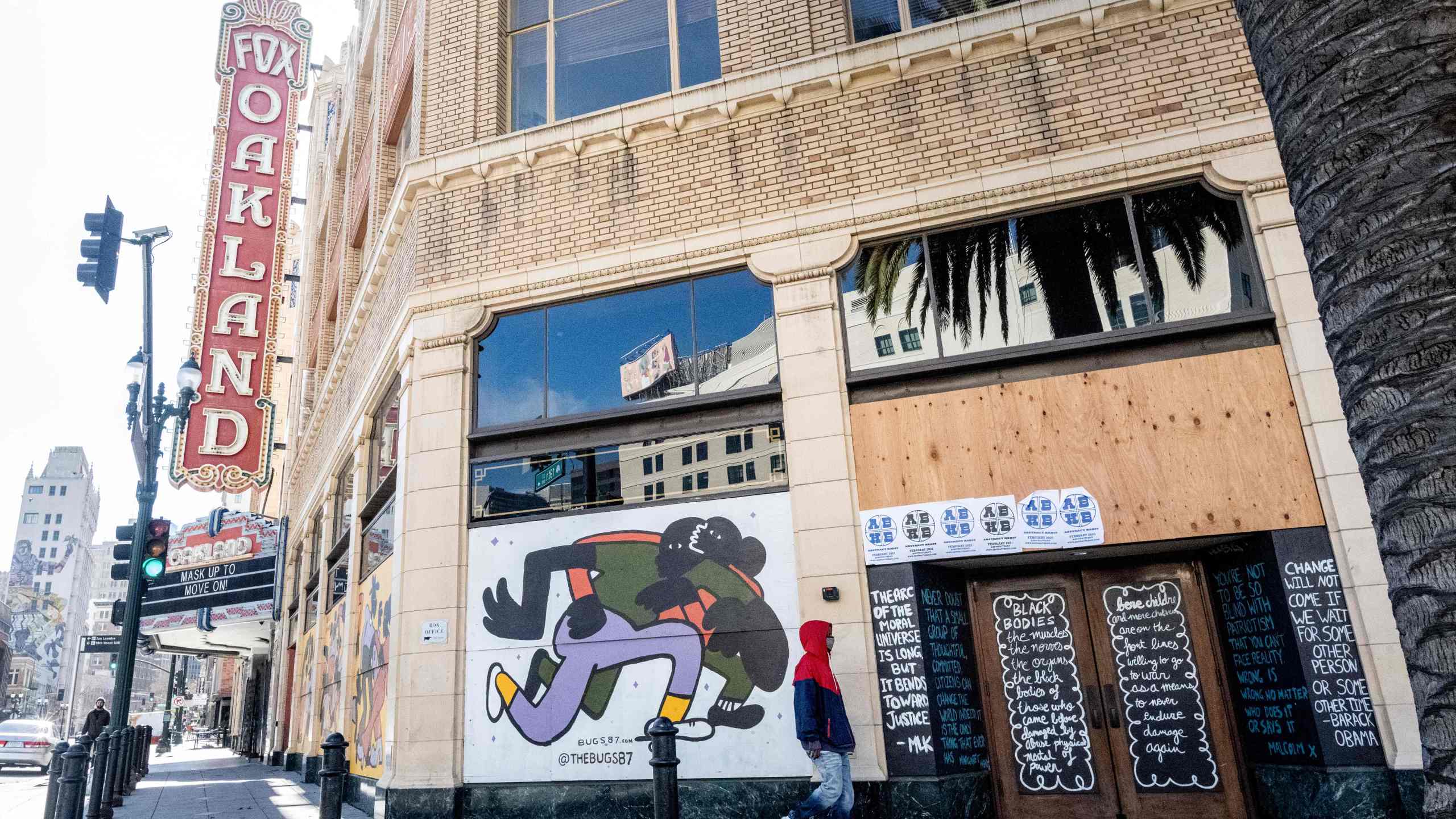 A person walks by a boarded-up shop in Oakland, California on February 12, 2021. (JOSH EDELSON/AFP via Getty Images)