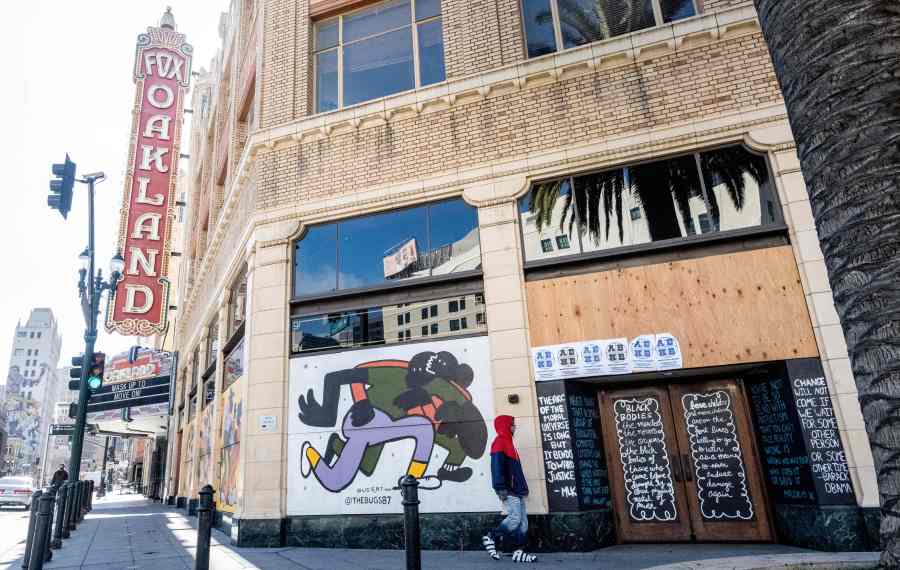 A person walks by a boarded-up shop in Oakland, California on February 12, 2021. (JOSH EDELSON/AFP via Getty Images)