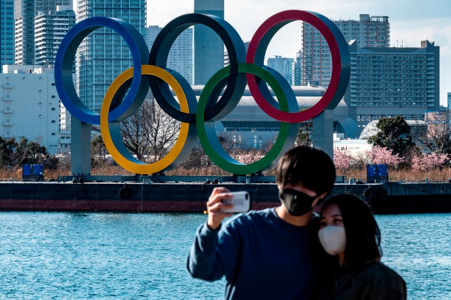 A couple pose for photos in front of the Olympic rings on display at the Odaiba waterfront in Tokyo on Feb. 24, 2021. (PHILIP FONG/AFP via Getty Images)