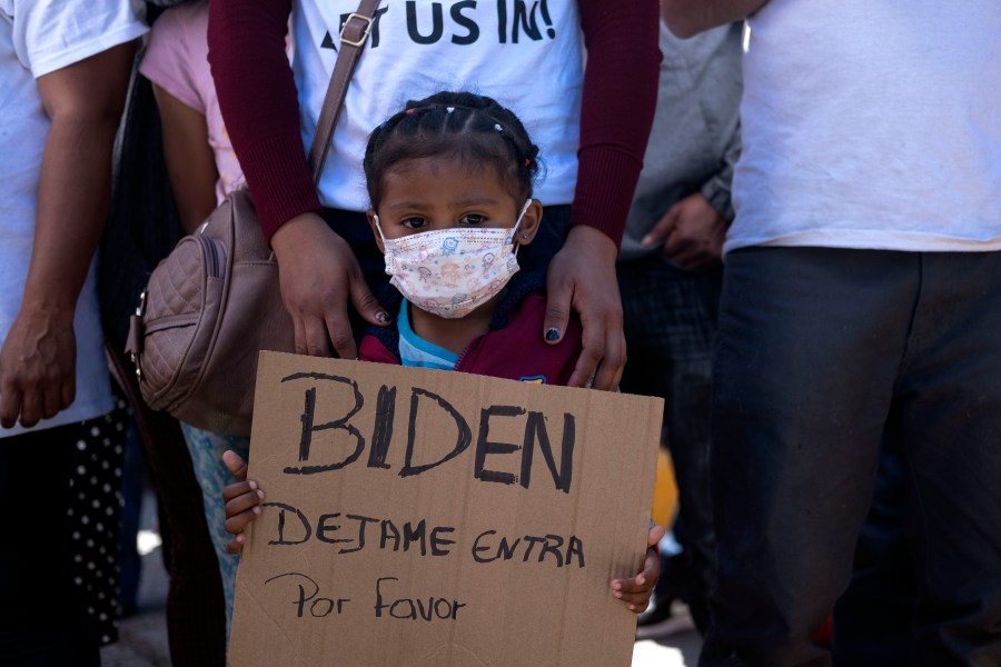 A girl from Honduras holds a sign asking President Joe Biden to let her in during a migrant demonstration demanding clearer U.S. migration policies at the San Ysidro crossing port in Tijuana, Mexico on March 2, 2021. (Guillermo Arias / AFP / Getty Images)