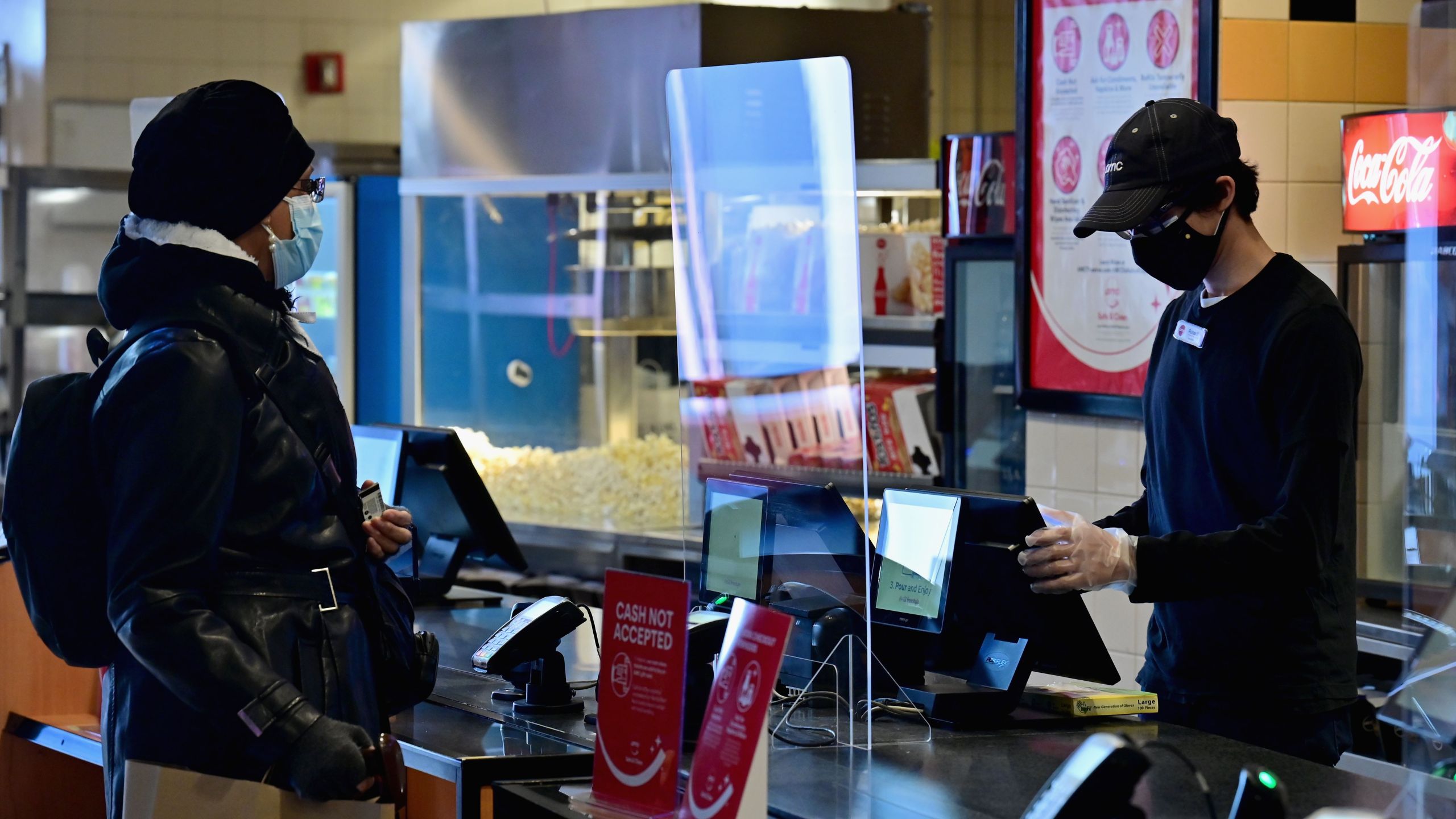 An employee helps a moviegoer with a concessions purchase at AMC Empire 25 off Times Square as New York City's cinemas reopen for the first time in a year following the coronavirus shutdown, on March 5, 2021, in New York City. (ANGELA WEISS/AFP via Getty Images)