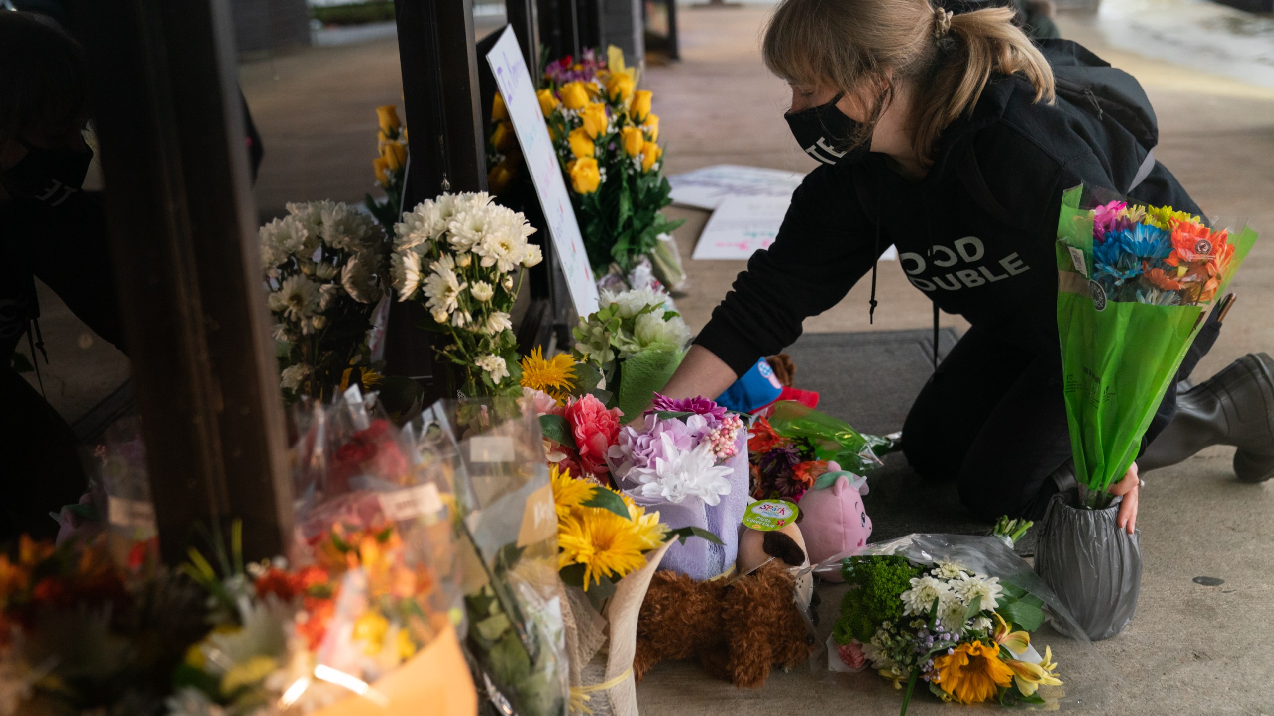 Shelby Swan adjusts flowers and signs outside Youngs Asian Massage where four people were shot and killed on March 17, 2021 in Acworth, Georgia. (Elijah Nouvelage/Getty Images)