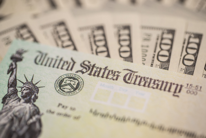 A U.S. Treasury check and cash are seen in a file photo. (iStock/Getty Images Plus)