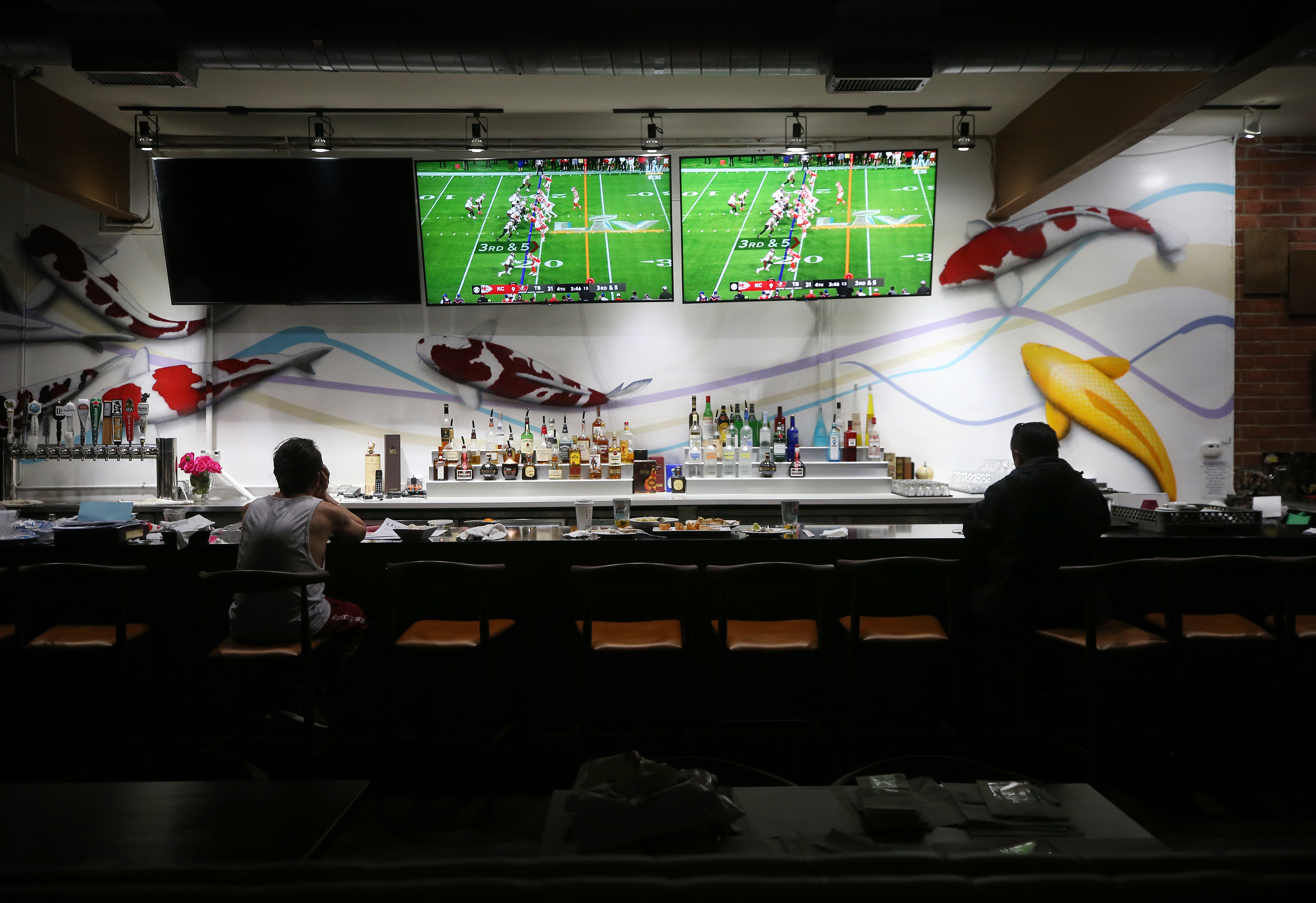 Restaurant workers sit during a break as Super Bowl LV plays on televisions in the shuttered indoor section of a restaurant on Feb. 7, 2021 in Los Angeles.(Mario Tama/Getty Images)