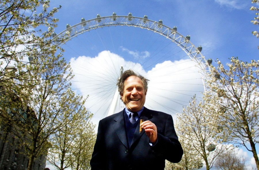 American actor George Segal smokes a cigar before setting off on a trip on the London Eye on April 19, 2001. (ADRIAN DENNIS/AFP via Getty Images)