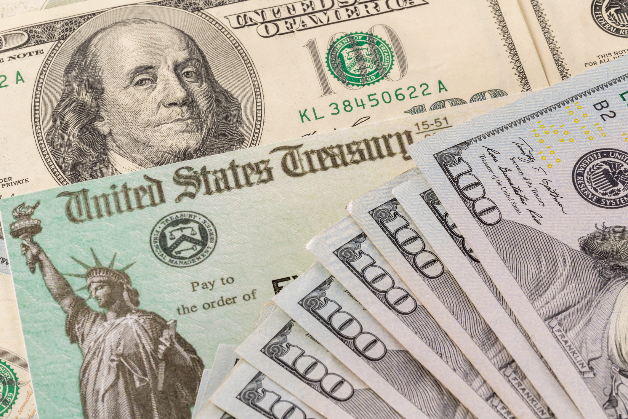 A federal stimulus check and $100 bills are seen in a file photo. (iStock/Getty Images Plus)