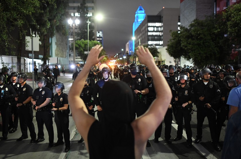 A protester faces a line of LAPD officers on Spring Street in downtown Los Angeles on May 29, 2020. (Wally Skalij / Los Angeles Times)