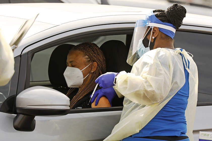 A motorist waits to be vaccinated by a health worker at the Forum, one of several mass COVID-19 vaccination sites in Los Angeles County.(Al Seib / Los Angeles Times)