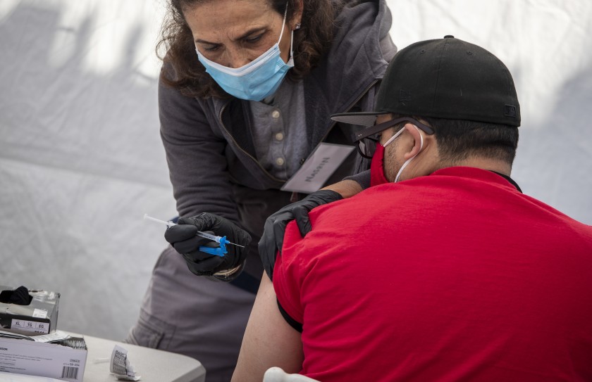 Pharmacist Nasrin Assil administers a Johnson & Johnson COVID-19 vaccine at Karsh Family Social Service Center’s pop-up clinic for older adults on Thursday in Los Angeles.(Brian van der Brug / Los Angeles Times)