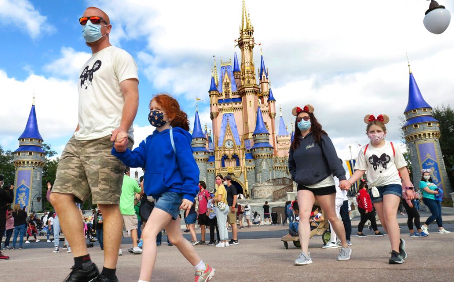 In this Dec. 21, 2020, file photo, a family walks past Cinderella Castle in the Magic Kingdom, at Walt Disney World in Lake Buena Vista, Fla. (Joe Burbank/Orlando Sentinel via AP, File)