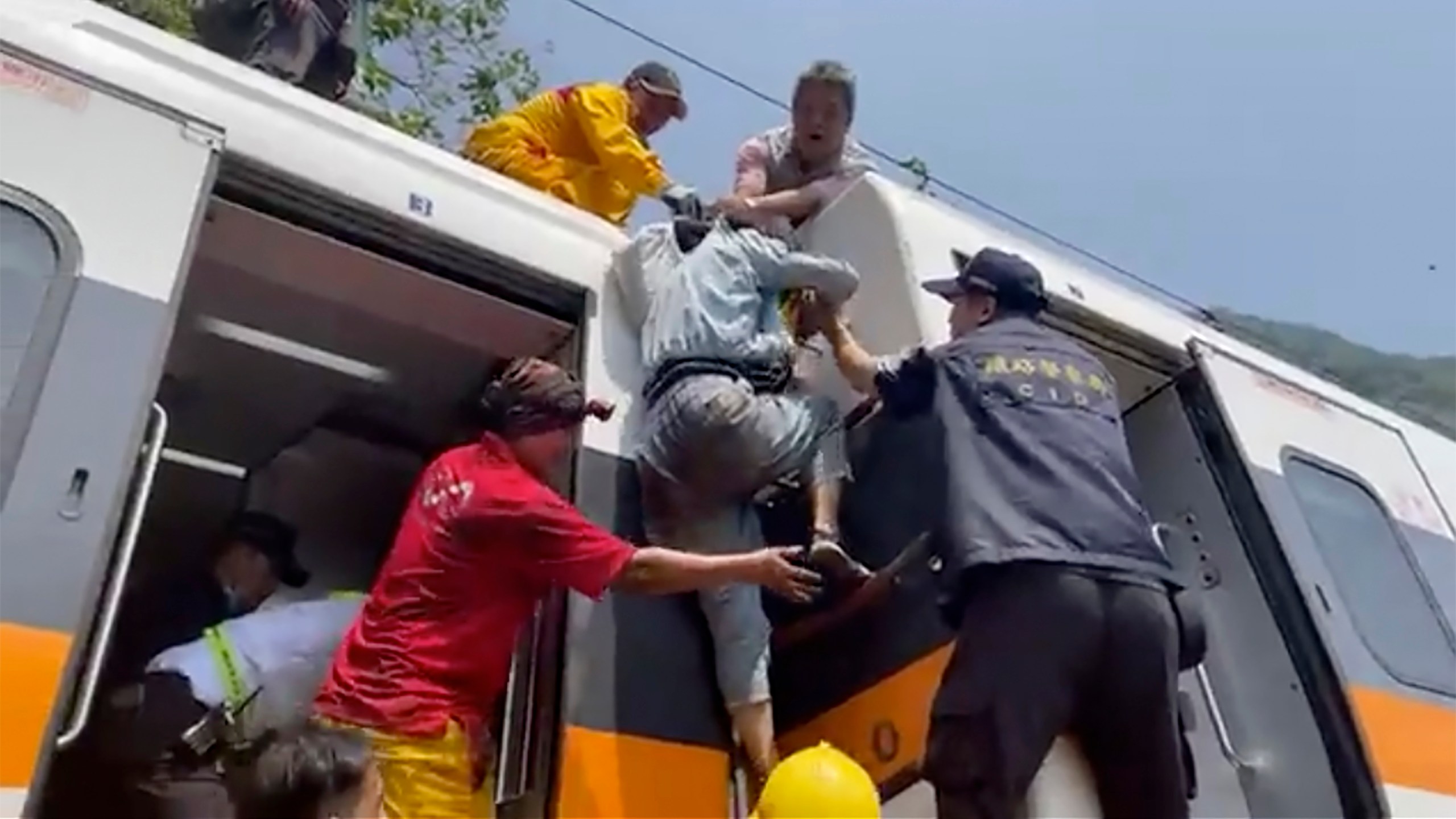 In this image made from a video released by hsnews.com.tw, a passenger, center, is helped to climb out of a derailed train in Hualien County in eastern Taiwan on April 2, 2021. The train partially derailed along Taiwan’s east coast Friday, injuring an unknown number of passengers and causing potential fatalities. (hsnews.com.tw via AP)