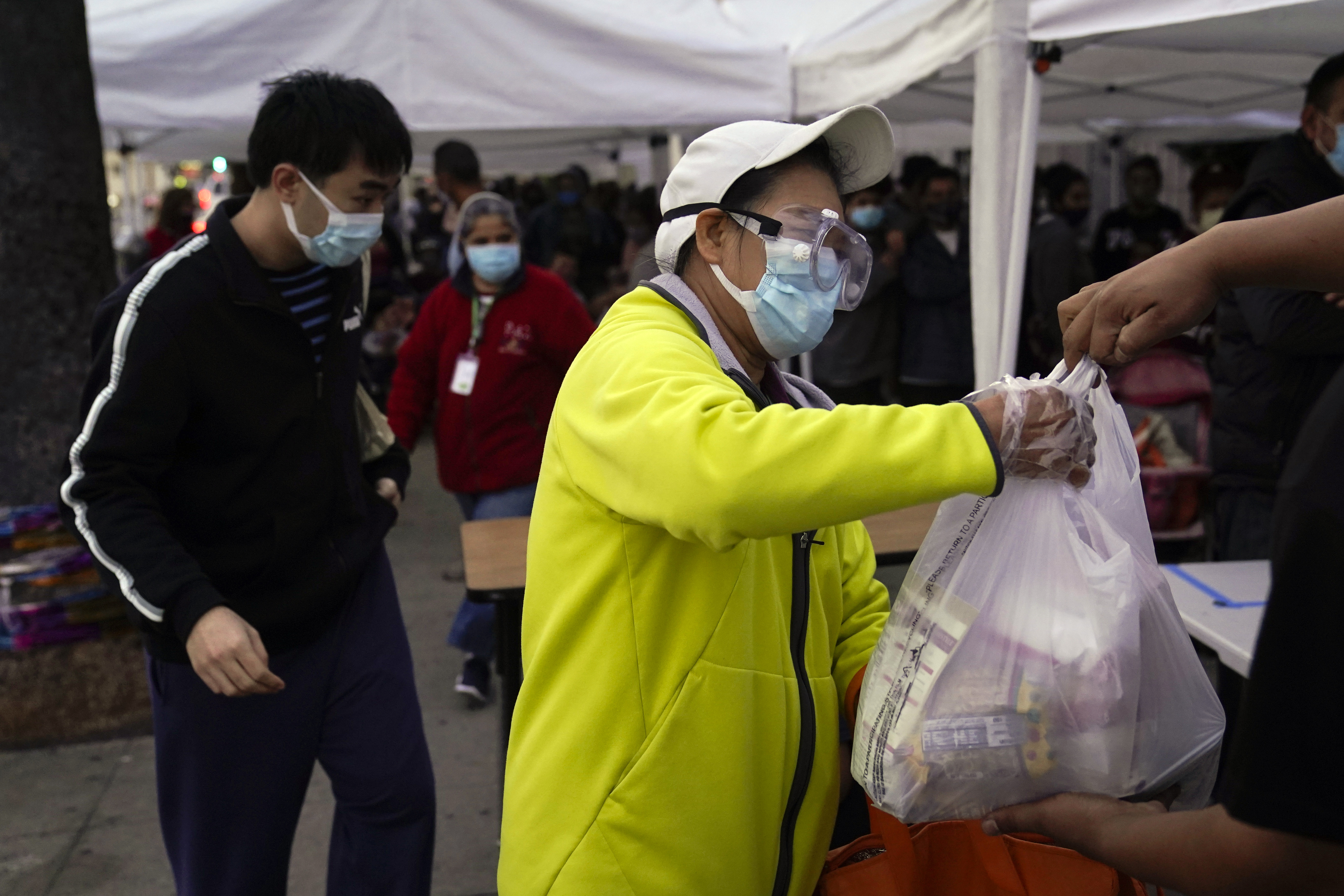 In this Dec. 17, 2020, file photo, a woman receives a bag of groceries at a food bank at the Los Angeles Boys & Girls Club in the Lincoln Heights neighborhood of Los Angeles. (AP Photo/Jae C. Hong, File)