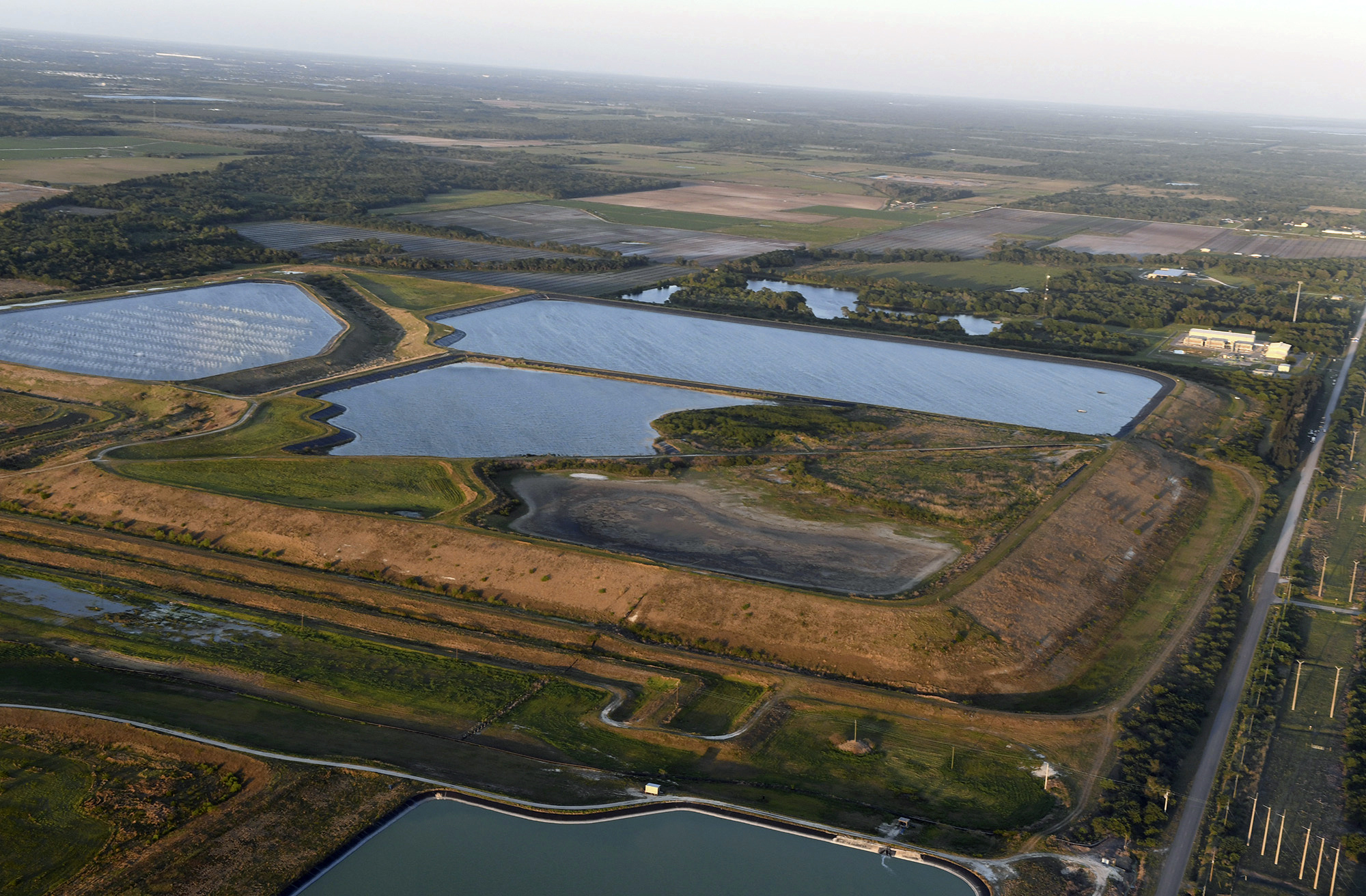 This aerial photo taken from an airplane shows a reservoir near the old Piney Point phosphate mine, Saturday, April 3, 2021 in Bradenton, Fla. Florida Gov. Ron DeSantis declared a state of emergency Saturday after a significant leak at a large pond of wastewater threatened to flood roads and burst a system that stores polluted waters. The pond where the leak was discovered is at the old Piney Point phosphate mine, sitting in a stack of phosphogypsum, a waste product from manufacturing fertilizer that is radioactive. (Tiffany Tompkins/The Bradenton Herald via AP)