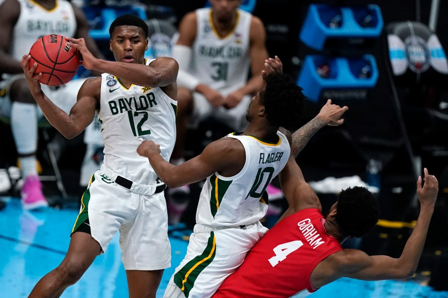 Baylor guard Jared Butler (12) passes over teammate guard Adam Flagler (10) and Houston forward Justin Gorham (4) during the first half of a men's Final Four NCAA college basketball tournament semifinal game, Saturday, April 3, 2021, at Lucas Oil Stadium in Indianapolis. (AP Photo/Michael Conroy)