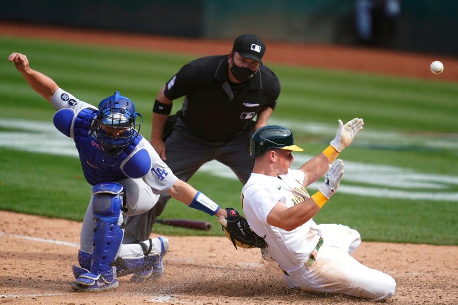 Oakland Athletics' Matt Chapman, right, slides home to score past Los Angeles Dodgers catcher Will Smith during the ninth inning of a baseball game in Oakland, Calif., Wednesday, April 7, 2021. (AP Photo/Jeff Chiu)