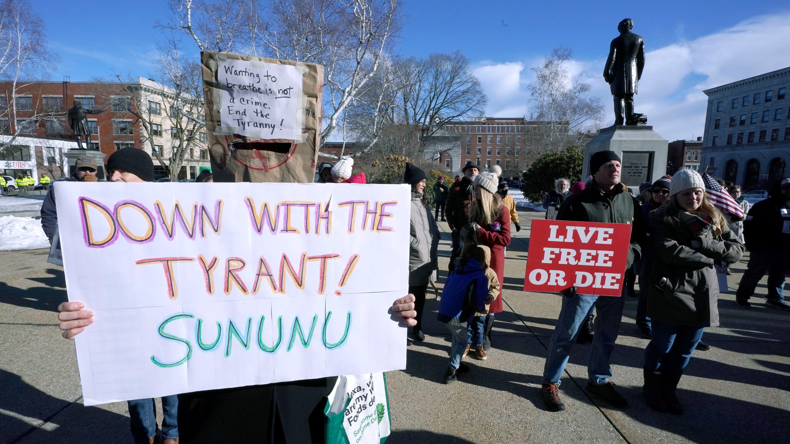 In this Thursday, Jan. 7, 2021 file photo, people protest outside the Statehouse in Concord, N.H., as Gov. Chris Sununu is inaugurated at noon for his third term as governor. A measure that recently passed New Hampshire's Republican-led House would prohibit governors from indefinitely renewing emergency declarations, as Sununu has done every 21 days for the past year. It would halt emergency orders after 30 days unless renewed by lawmakers. (AP Photo/Charles Krupa)