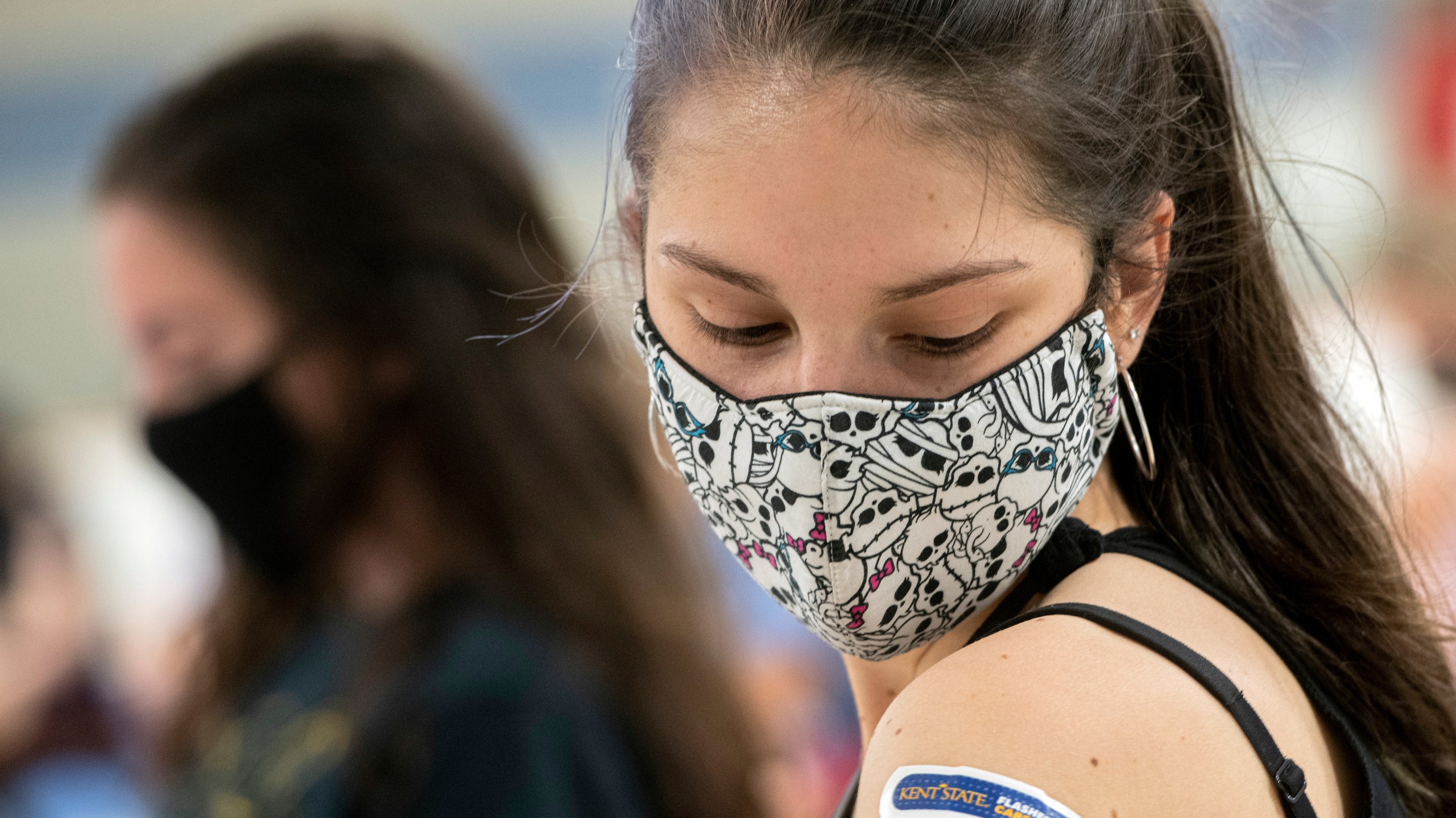 Kent State University student Regan Raeth of Hudson, Ohio, looks at her vaccination bandage as she waits for 15 minutes after her shot in Kent, Ohio, Thursday, April 8, 2021. (AP Photo/Phil Long)