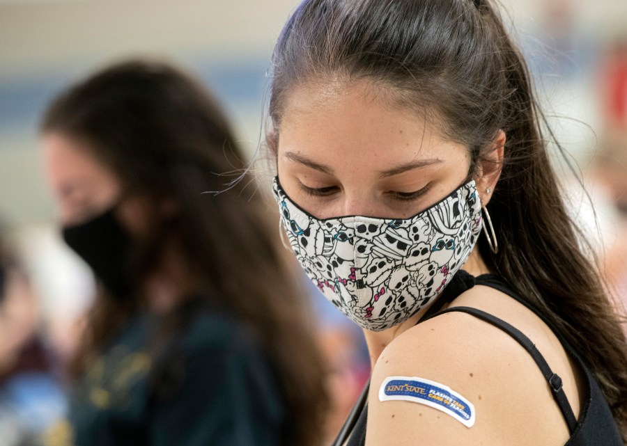 Kent State University student Regan Raeth of Hudson, Ohio, looks at her vaccination bandage as she waits for 15 minutes after her shot in Kent, Ohio, Thursday, April 8, 2021. (AP Photo/Phil Long)