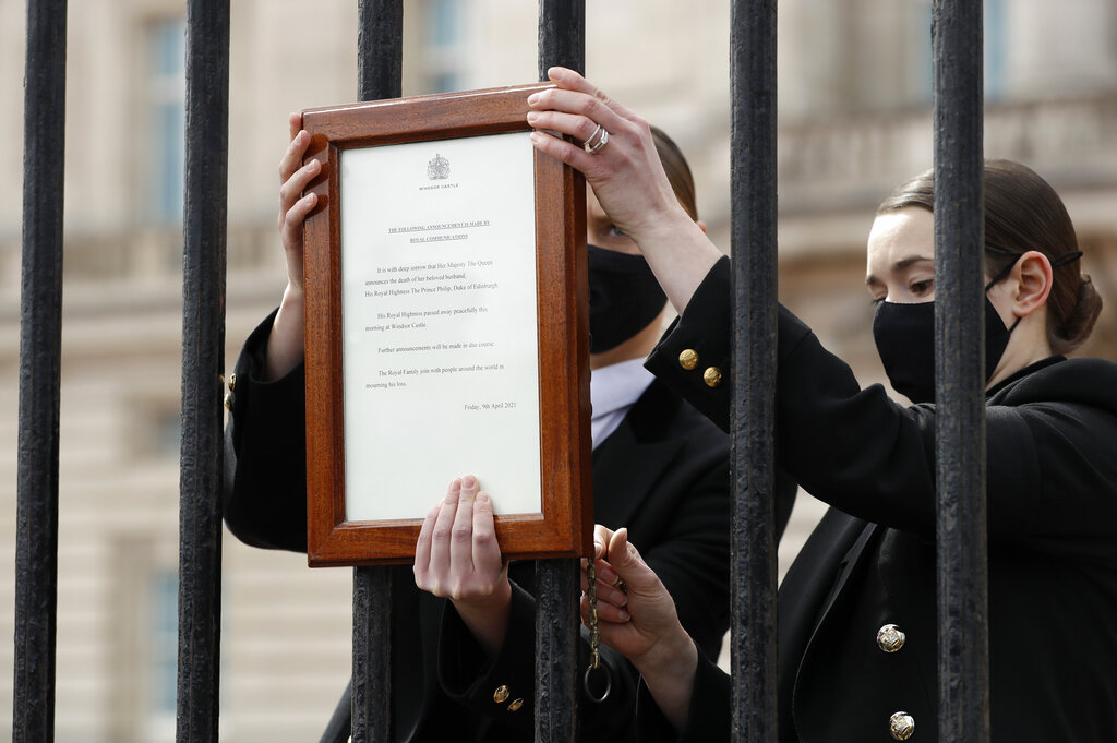 Members of staff attach an announcement, regarding the death of Britain's Prince Philip, to the fence of Buckingham Palace in London, Friday, April 9, 2021. (AP Photo/Matt Dunham)