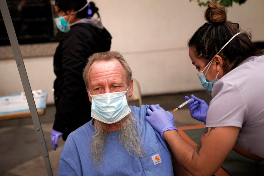 In this Feb. 3, 2021, file photo, EMT Rachel Bryant, right, administers a COVID-19 vaccine to a homeless man in the courtyard of the Midnight Mission in Los Angeles. (AP Photo/Jae C. Hong)