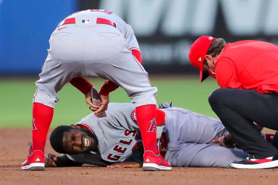 Los Angeles Angels manager Joe Maddon, top, leans over to check on Dexter Fowler who was injured during a play at second base against the Toronto Blue Jays during the second inning of a baseball game Friday, April 9, 2021, in Dunedin, Fla. (AP Photo/Mike Carlson)