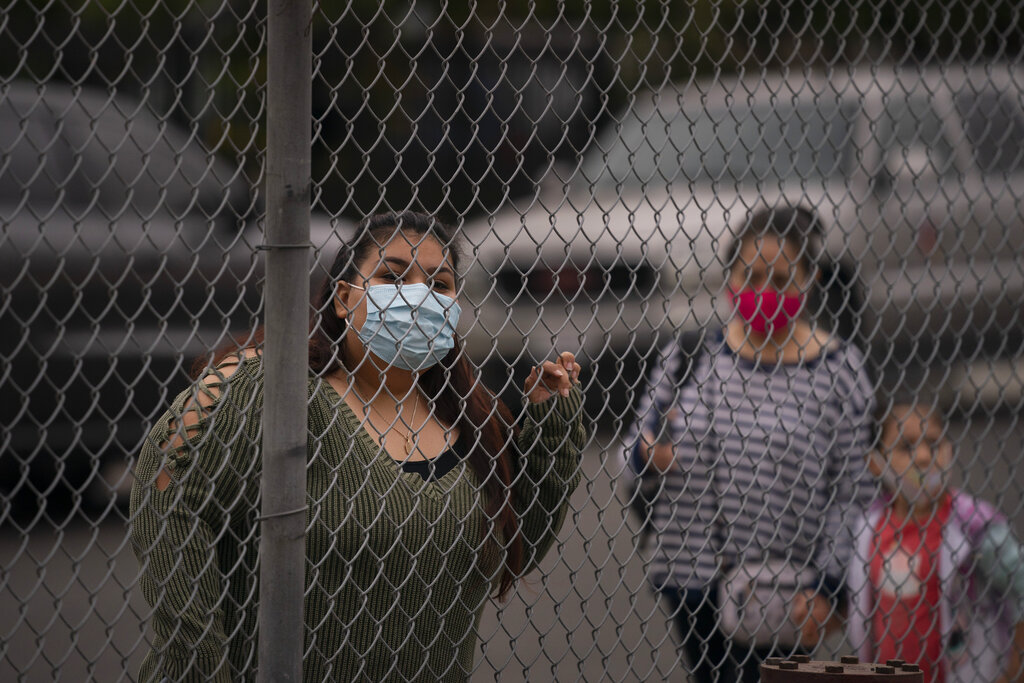 Griselda Saelak looks through a fence after dropping off her daughter on the first day of in-person learning at Heliotrope Avenue Elementary School in Maywood. (AP Photo/Jae C. Hong)