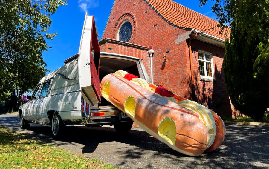 This photo provided by Ross Hall, shows a cream doughnut shaped coffin for the funeral of Phil McLean outside a church in Tauranga, New Zealand on Feb 17, 2021. (Ross Hall via AP)