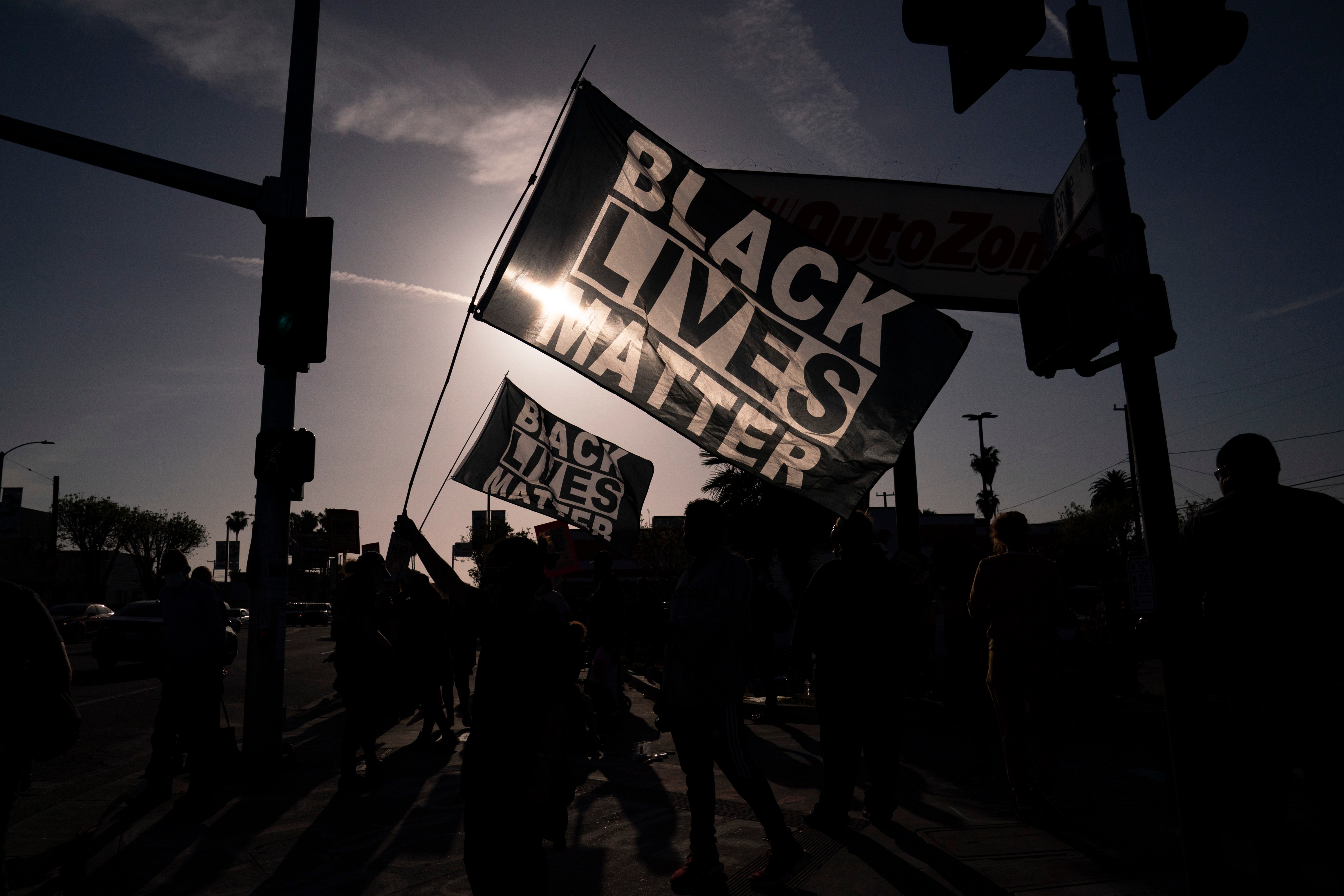 People hold Black Lives Matter flags at the intersection of Florence and Normandie avenues, on April 20, 2021, in Los Angeles, after a guilty verdict was announced at the trial of former Minneapolis police Officer Derek Chauvin for the 2020 death of George Floyd. (AP Photo/Jae C. Hong)