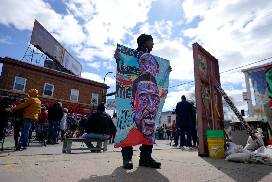 A man holds a sign at George Floyd Square, Wednesday, April 21, 2021, in Minneapolis, a day after former Minneapolis police Officer Derek Chauvin was convicted on all counts for the 2020 death of Floyd. (AP Photo/Julio Cortez)