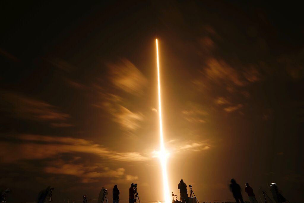 In this long exposure photo, photographers watch a SpaceX Falcon 9 rocket with the Crew Dragon space capsule lifts off from pad 39A at the Kennedy Space Center in Cape Canaveral, Fla., Friday, April 23, 2021. (AP Photo/Brynn Anderson)