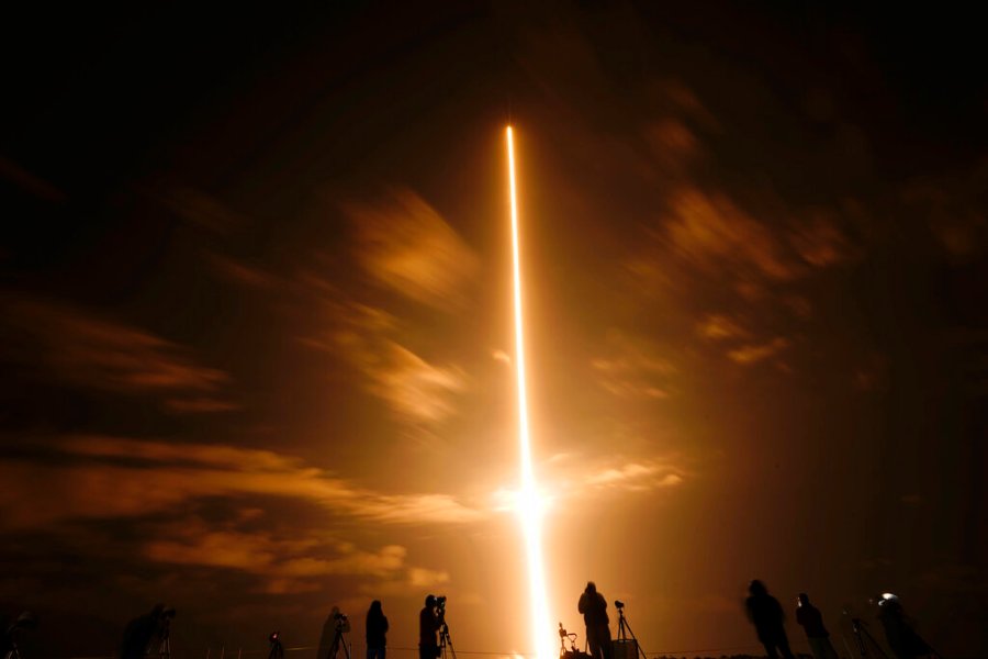 In this long exposure photo, photographers watch a SpaceX Falcon 9 rocket with the Crew Dragon space capsule lifts off from pad 39A at the Kennedy Space Center in Cape Canaveral, Fla., Friday, April 23, 2021. (AP Photo/Brynn Anderson)