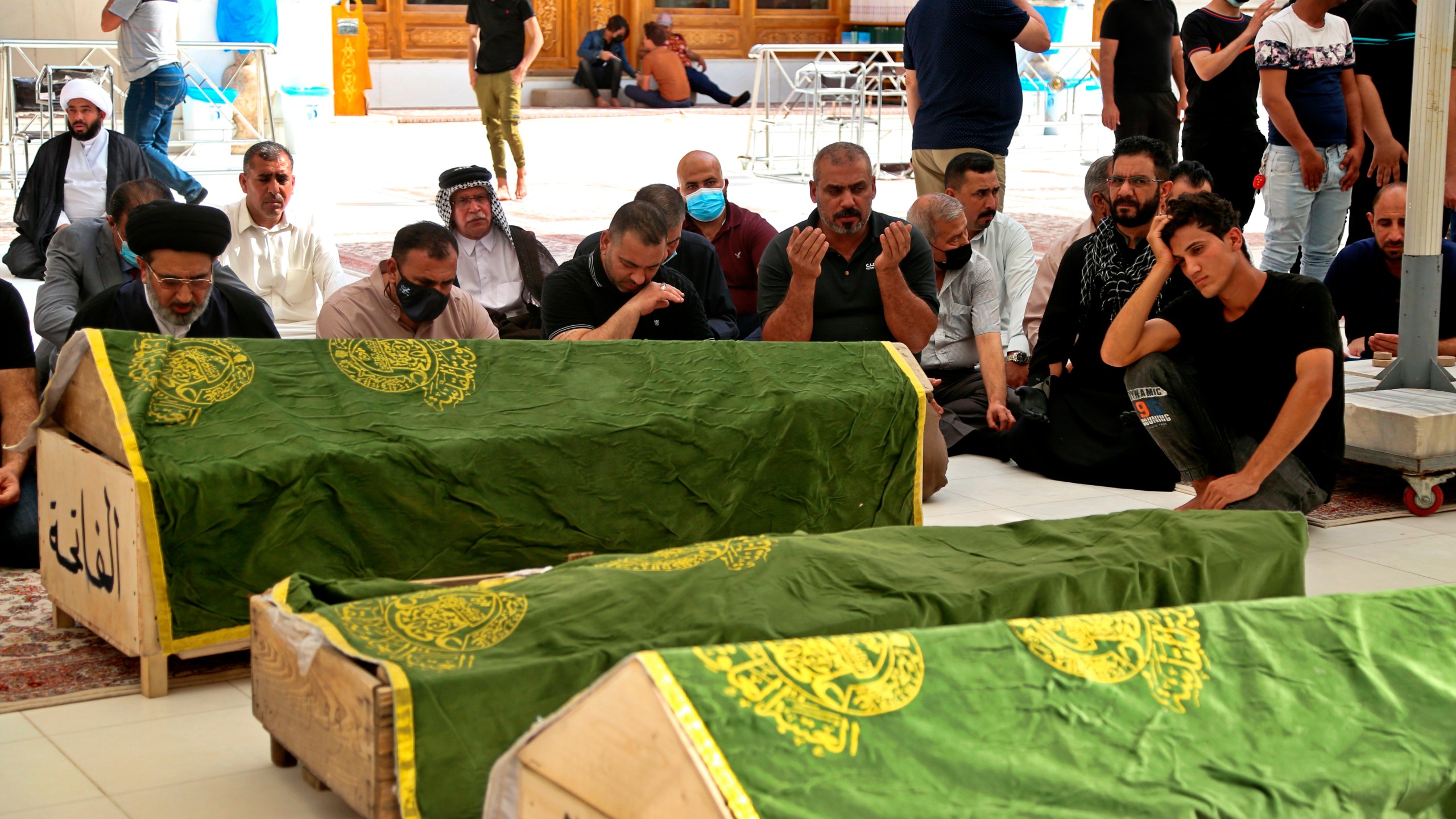 Mourners pray near the coffins of coronavirus patients who were killed in a hospital fire in Iraq, April 25, 2021. (AP Photo/Anmar Khalil)