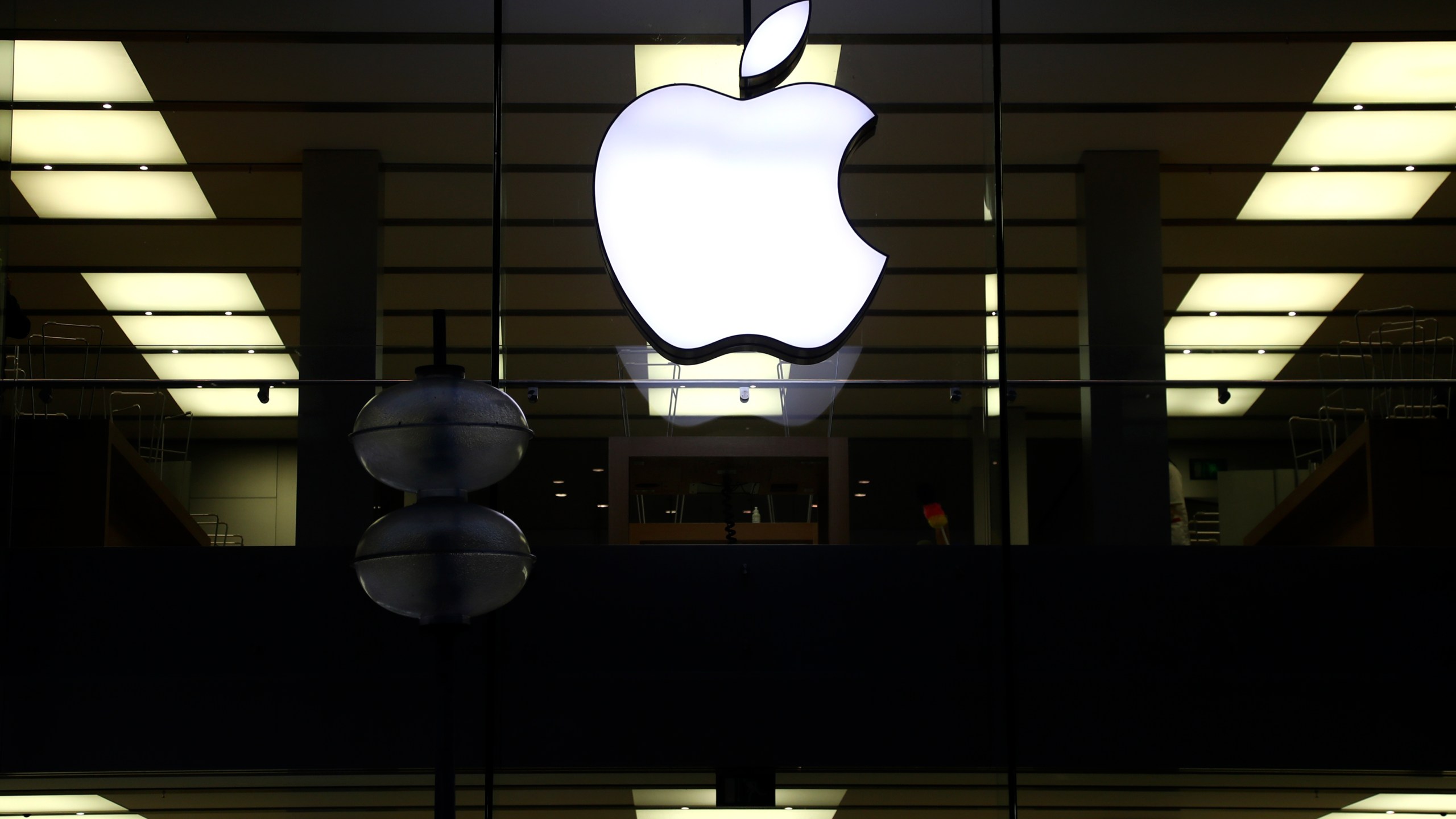 This Dec. 16, 2020 file photo shows an illuminated Apple logo at a store in Munich, Germany. Apple is following through on its pledge to crack down Facebook and other snoopy apps that secretly shadow people on their iPhones to help sell more advertising. The new privacy feature, dubbed “App Tracking Transparency,” rolled out Monday, April 26, 2021, as part of an update to the operating system powering the iPhone and iPad. (AP Photo/Matthias Schrader, File)