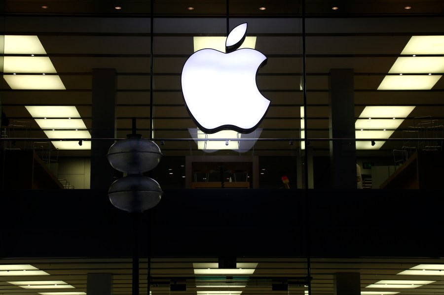 This Dec. 16, 2020 file photo shows an illuminated Apple logo at a store in Munich, Germany. Apple is following through on its pledge to crack down Facebook and other snoopy apps that secretly shadow people on their iPhones to help sell more advertising. The new privacy feature, dubbed “App Tracking Transparency,” rolled out Monday, April 26, 2021, as part of an update to the operating system powering the iPhone and iPad. (AP Photo/Matthias Schrader, File)