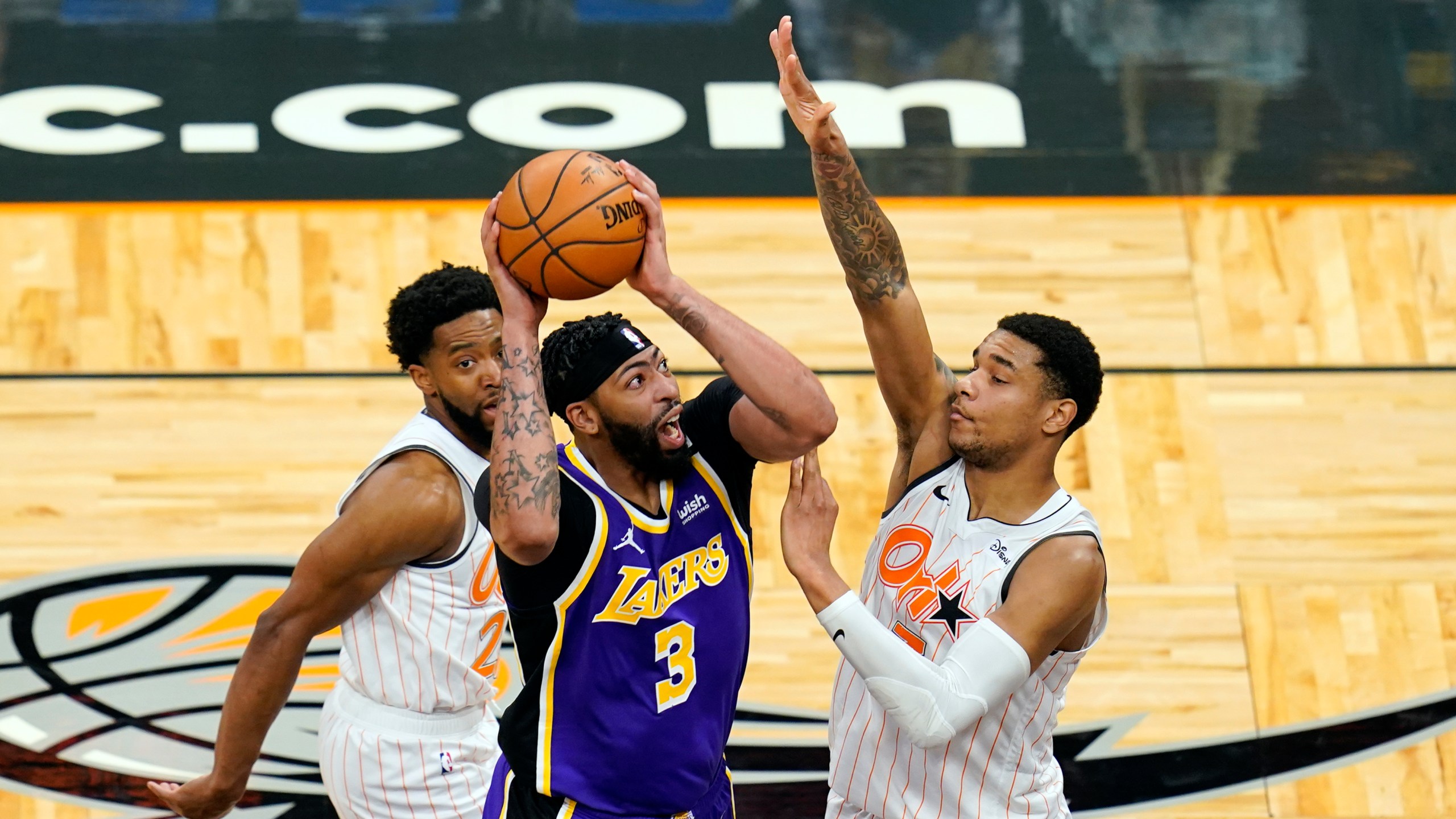 Los Angeles Lakers forward Anthony Davis takes shot as he gets between Orlando Magic guard Chasson Randle, left, and forward Chuma Okeke during the first half of an NBA basketball game in Orlando, Fla., on April 26, 2021. (John Raoux / Associated Press)