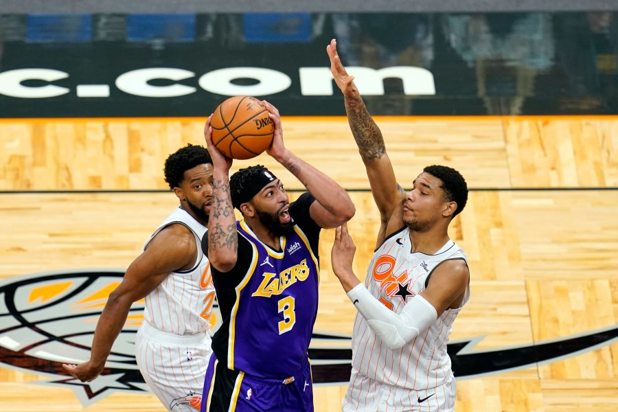 Los Angeles Lakers forward Anthony Davis takes shot as he gets between Orlando Magic guard Chasson Randle, left, and forward Chuma Okeke during the first half of an NBA basketball game in Orlando, Fla., on April 26, 2021. (John Raoux / Associated Press)