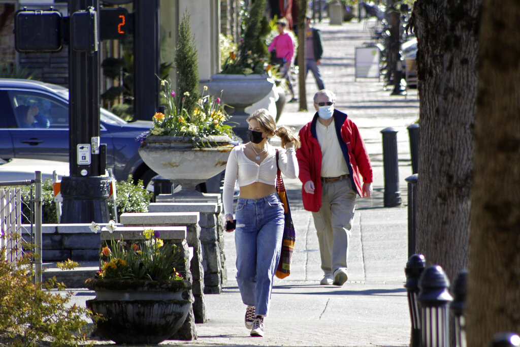 In this April 11, 2021, file photo, residents wearing masks walk in downtown Lake Oswego, Oregon. (AP Photo/Gillian Flaccus, File)