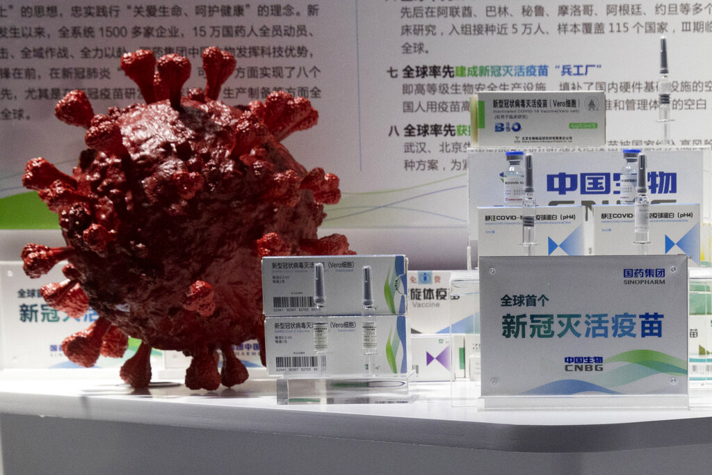 In this file photo taken Sept. 6, 2020, samples of a COVID-19 vaccine produced by Sinopharm subsidiary CNBG are displayed near a 3D model of a coronavirus during a trade fair in Beijing. (AP Photo/Ng Han Guan, File)