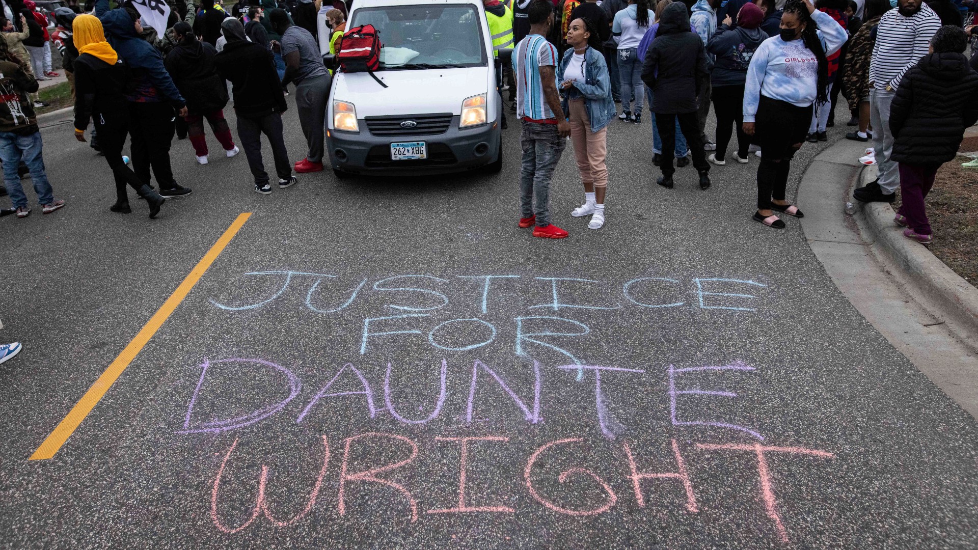 People gather in protest, Sunday, April 11, 2021, in Brooklyn Center, Minn. The family of Daunte Wright, 20, told a crowd that he was shot by police Sunday before getting back into his car and driving away, then crashing the vehicle several blocks away. The family said Wright was later pronounced dead. (AP Photo/Christian Monterrosa)