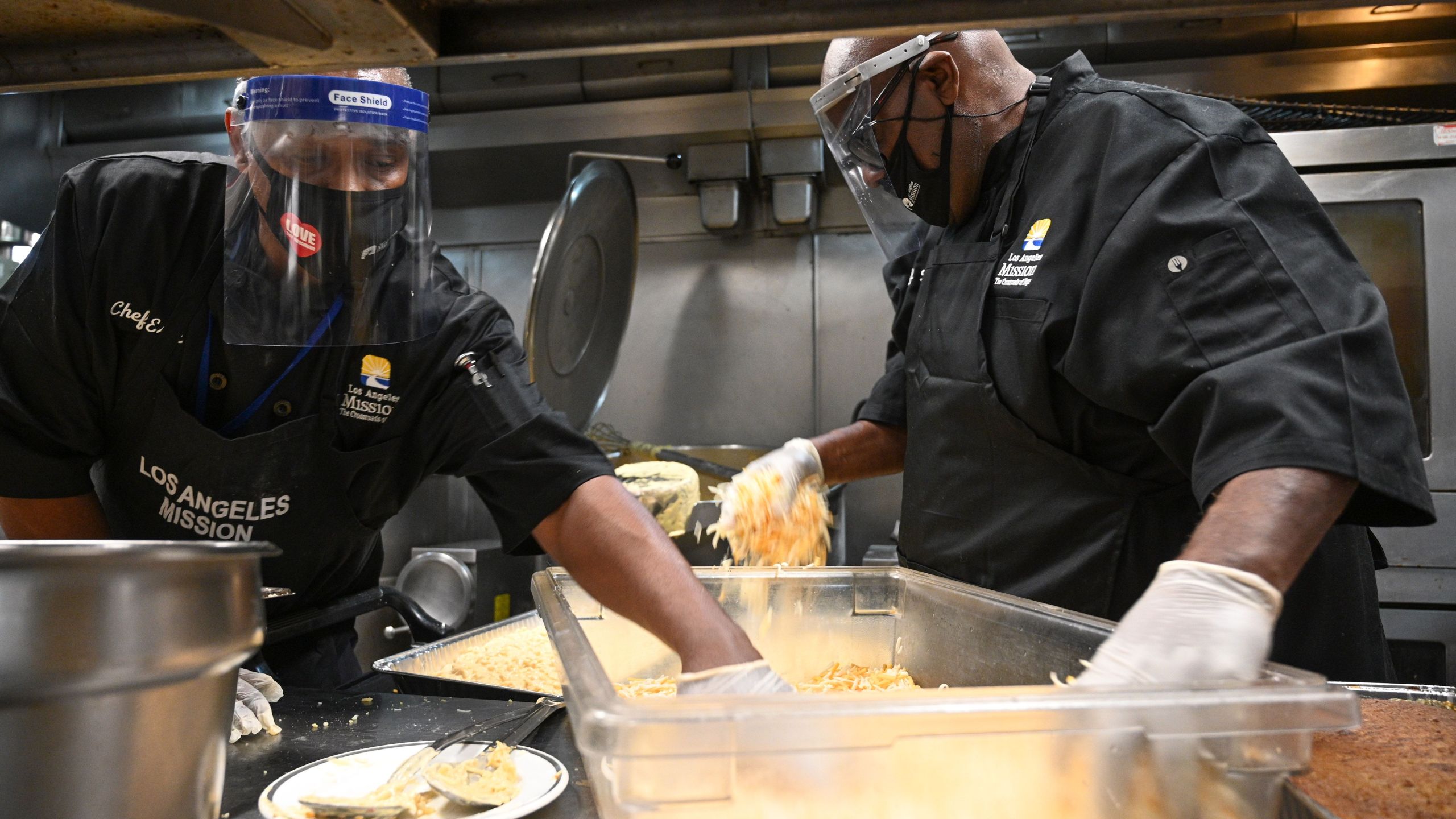 Chefs Erik Grant (L) and David Thomas prepare macaroni and cheese casserole as part of a traditional Thanksgiving dinner to be distributed for those in need at the Los Angeles Mission on Skid Row, November 25, 2020 in Los Angeles, California.(ROBYN BECK/AFP via Getty Images)