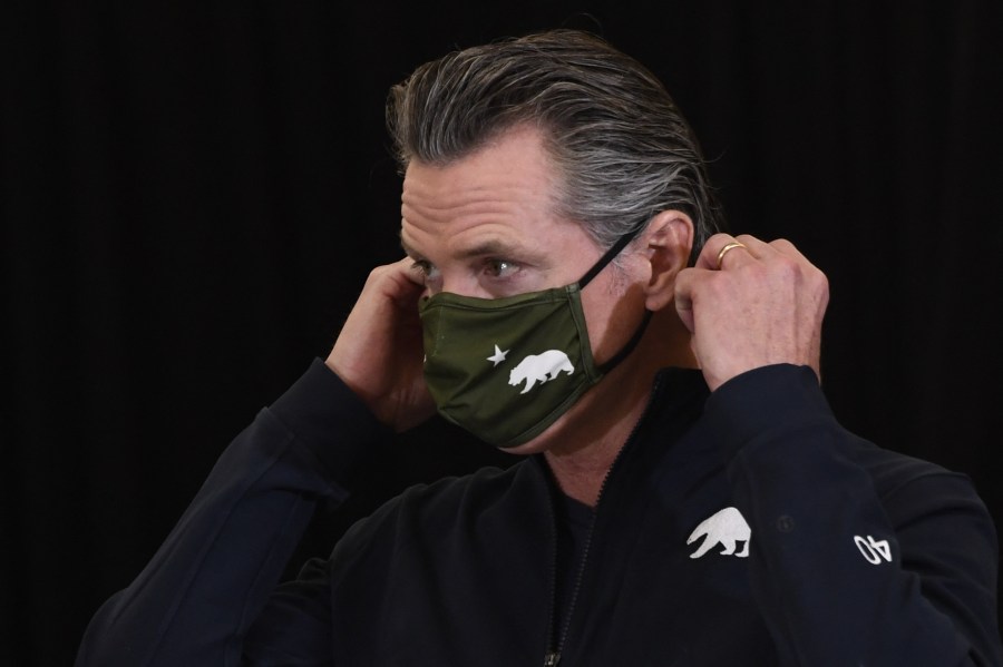 California Governor Gavin Newsom puts on his facemask after speaking to the media in Los Angeles on April 1, 2021. (PATRICK T. FALLON/AFP via Getty Images)